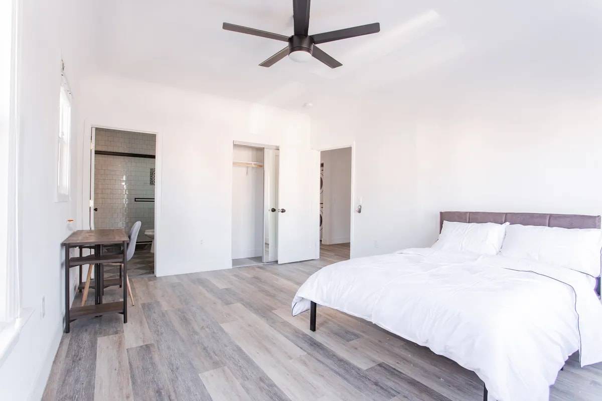Spacious bedroom with a door open to a private bathroom, a closet, and a stacked washer and dryer visible through the doorway